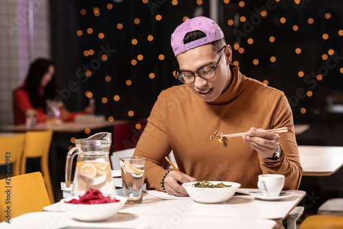 Customer feeling unhappy about ordered dish in restaurant and holding it with chopsticks. photo