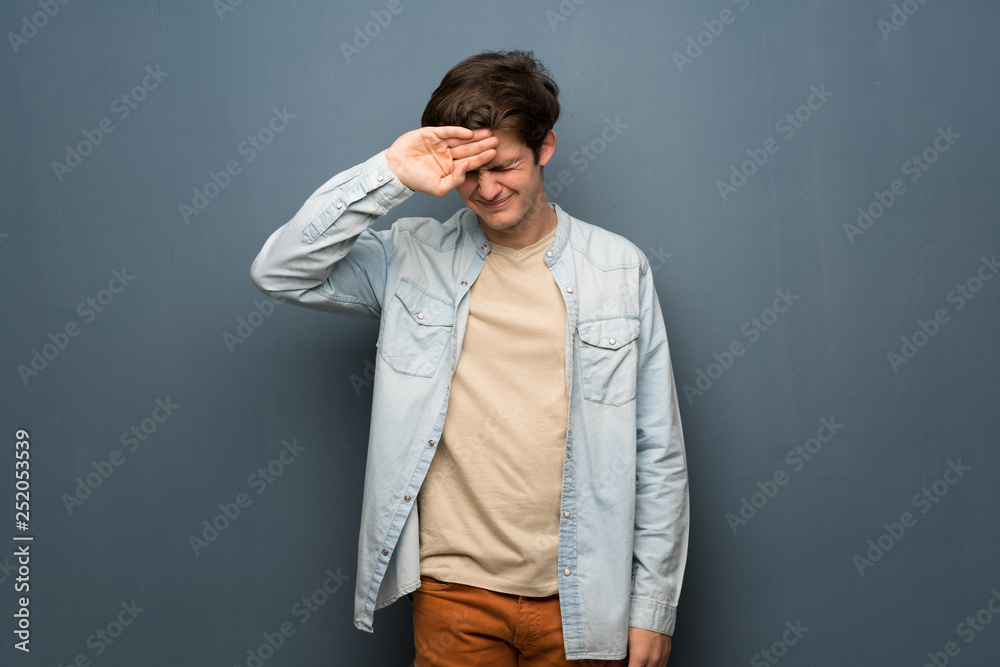 Teenager man with jean jacket over grey wall with tired and sick expression