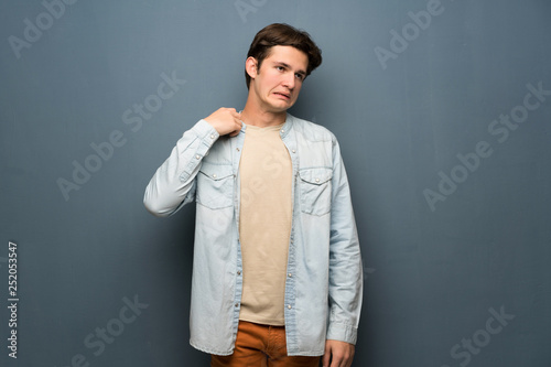 Teenager man with jean jacket over grey wall with tired and sick expression