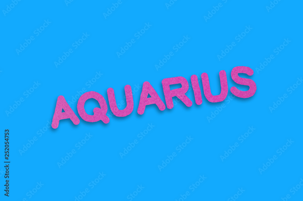Word aquarius cut out of purple paper on blue table. Top view. Horoscope concept
