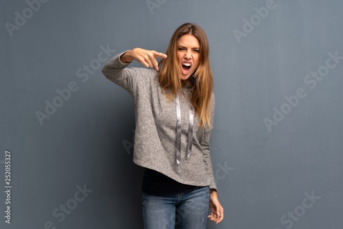 Blonde woman over grey background frustrated and pointing to the front © luismolinero