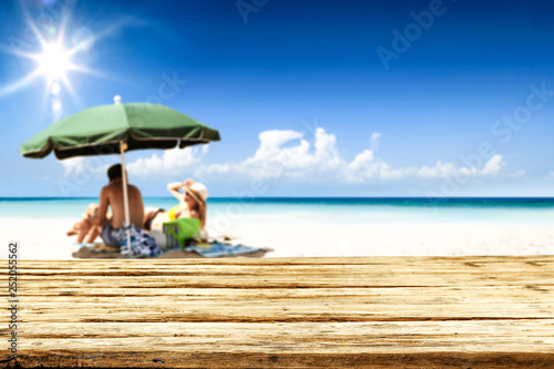 Desk of free space for your product. Beach landscape with people on towel. Ocean water and sun light