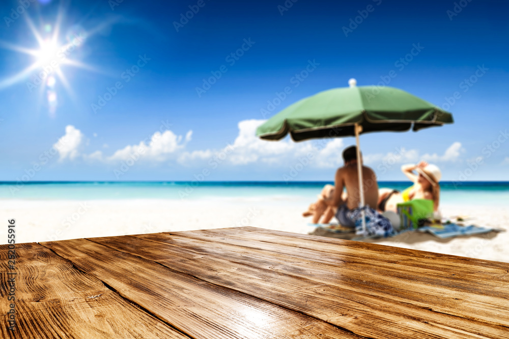 Desk of free space for your product. Beach landscape with people on towel. Ocean water and sun light