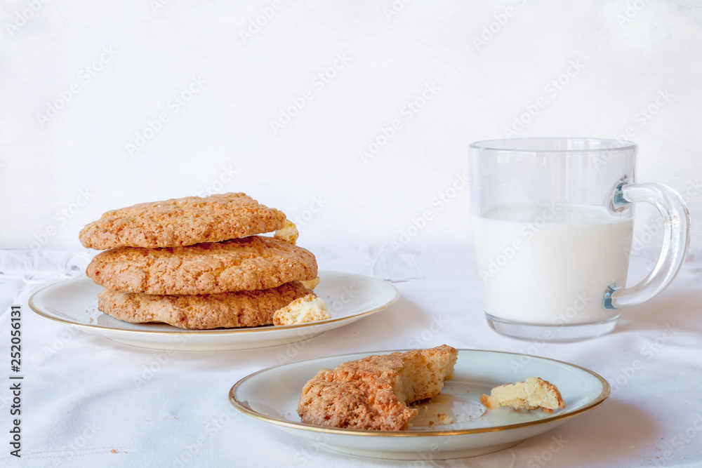 Traditional American chips cookies childhood breakfast snack with bite piece and milk glass on white table copyspace Traditional American chips cookies childhood breakfast snack with bite piece and milk glass on white table copyspace