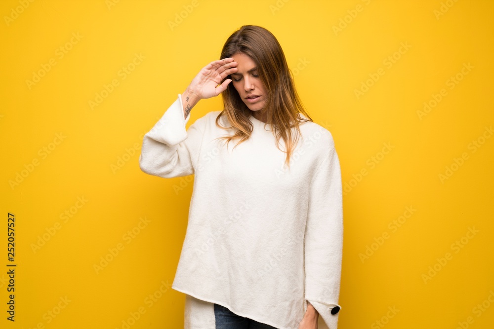 Blonde woman over yellow wall with tired and sick expression Blonde woman over yellow wall with tired and sick expression