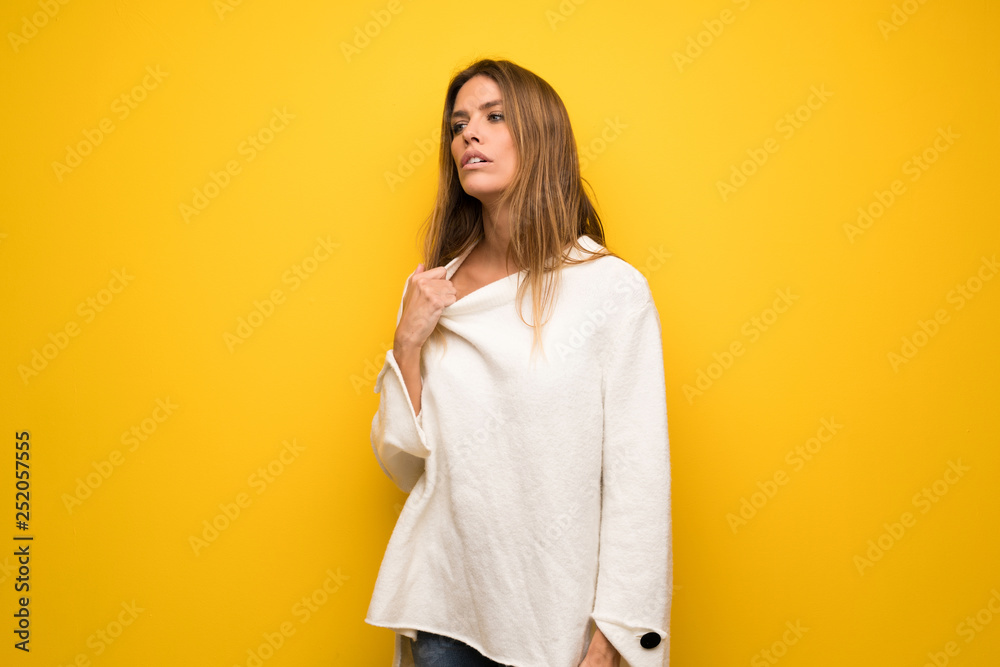 Blonde woman over yellow wall with tired and sick expression Blonde woman over yellow wall with tired and sick expression