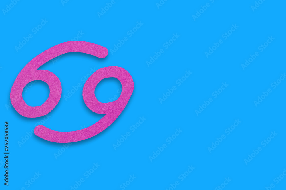 Symbol of astrological sign cancer cut out of purple paper on blue table. Top view. Horoscope concept. Copy space for your text Symbol of astrological sign cancer cut out of purple paper on blue table. Top view. Horoscope concept. Copy space for your text
