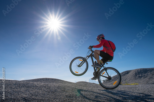 Cyclist riding mountain bike on the rocky trail at sunset. Extreme mountain bike sport athlete man riding outdoors lifestyle trail. 
