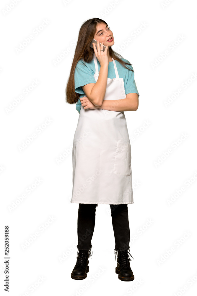 Full-length shot of Girl with apron keeping a conversation with the mobile phone on isolated white background Full-length shot of Girl with apron keeping a conversation with the mobile phone on isolated white background