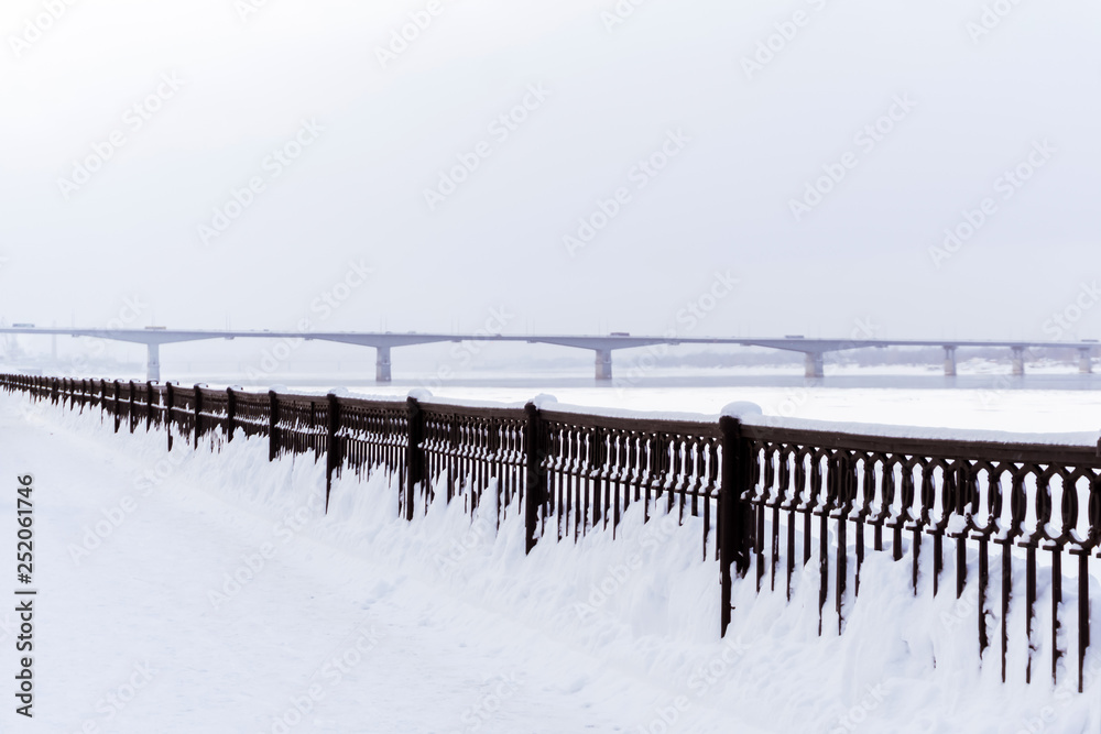 frozen river, quay fence and road bridge away