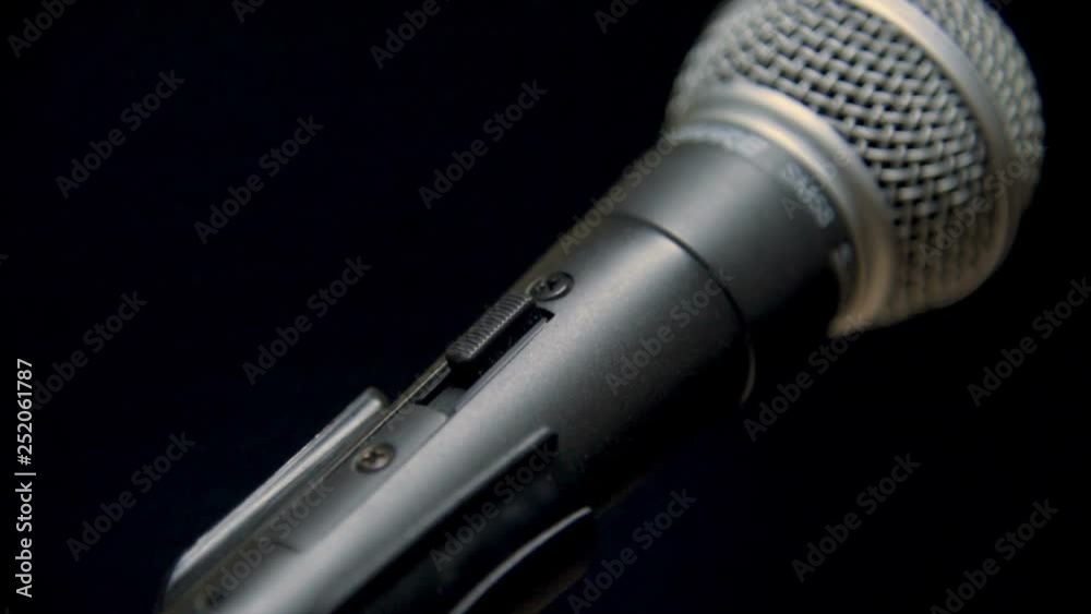 Hand turning on a microphone on a dark background Hand turning on a microphone on a dark background
