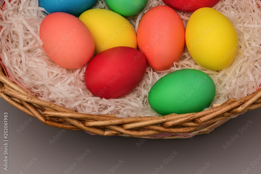 Easter colored eggs in nest on grey background