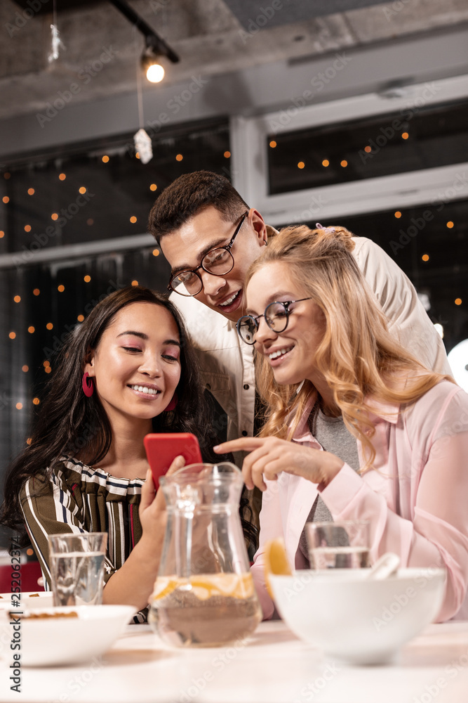 Girl seeing familiar face while watching photo on the phone of her female friend which she showing. Girl seeing familiar face while watching photo on the phone of her female friend which she showing.