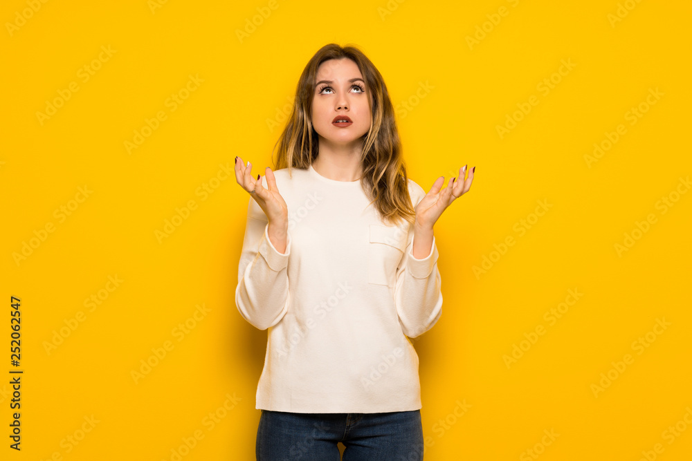 Teenager girl over yellow wall frustrated by a bad situation Teenager girl over yellow wall frustrated by a bad situation