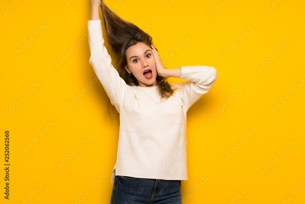 Teenager girl over yellow wall showing tongue at the camera having funny look Teenager girl over yellow wall showing tongue at the camera having funny look