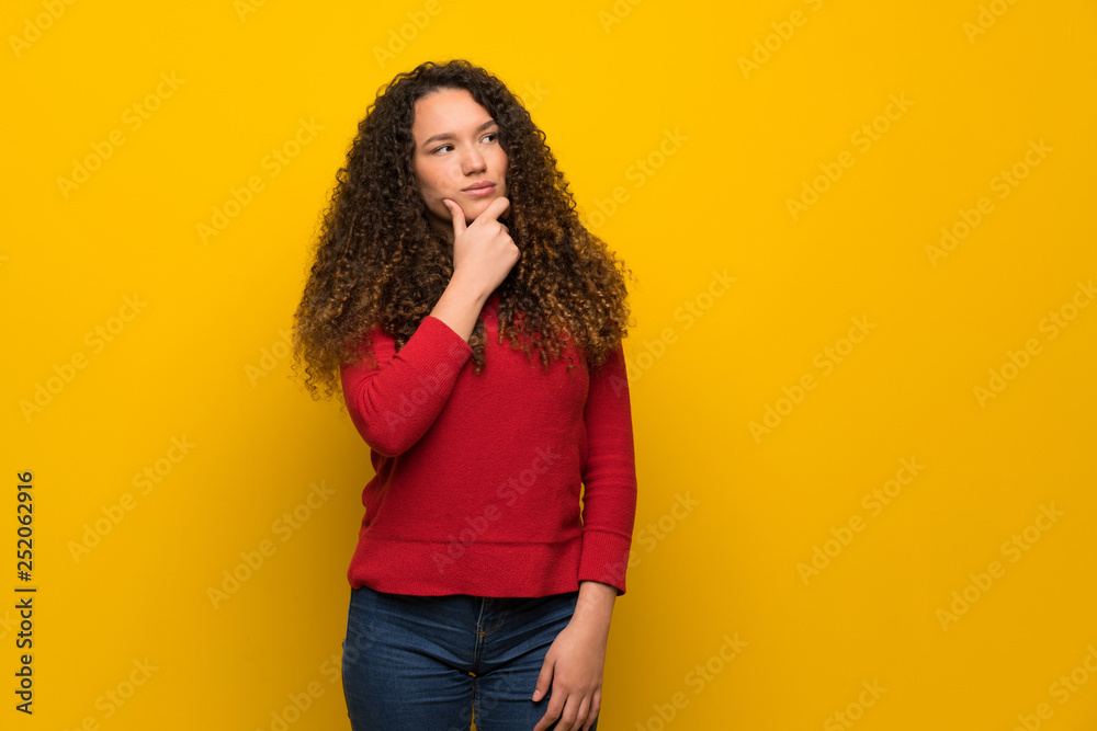 Teenager girl with red sweater over yellow wall thinking Teenager girl with red sweater over yellow wall thinking
