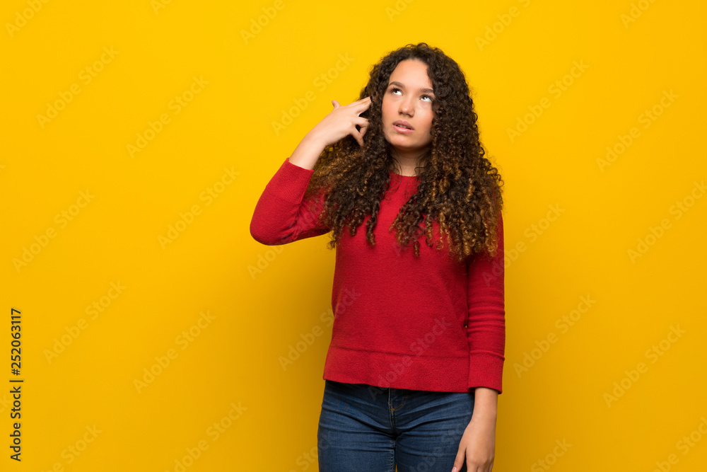 Teenager girl with red sweater over yellow wall with problems making suicide gesture Teenager girl with red sweater over yellow wall with problems making suicide gesture