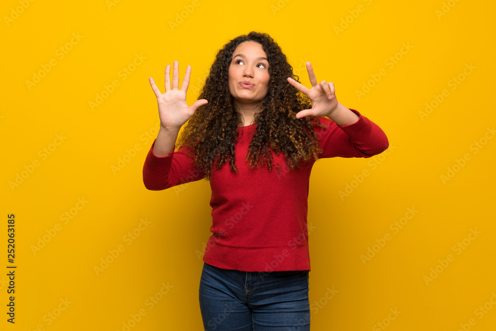 Teenager girl with red sweater over yellow wall counting eight with fingers Teenager girl with red sweater over yellow wall counting eight with fingers