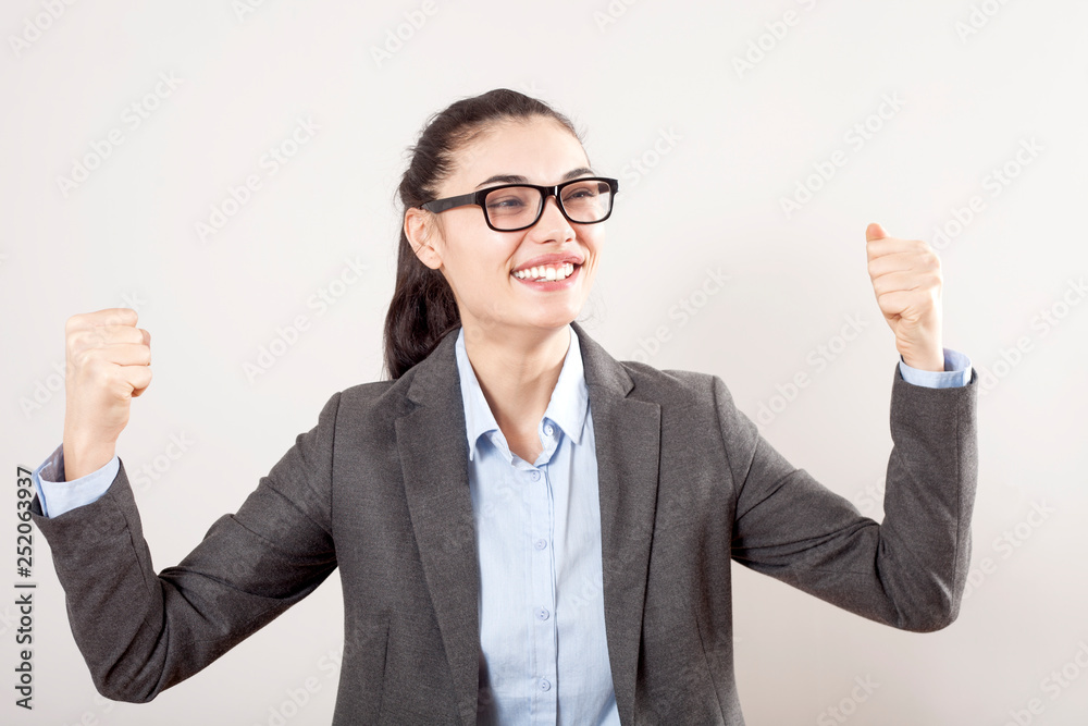 Success in business or career. Enthusiastic businesswoman with raised arms cheering in isolated on grey background Success in business or career. Enthusiastic businesswoman with raised arms cheering in isolated on grey background