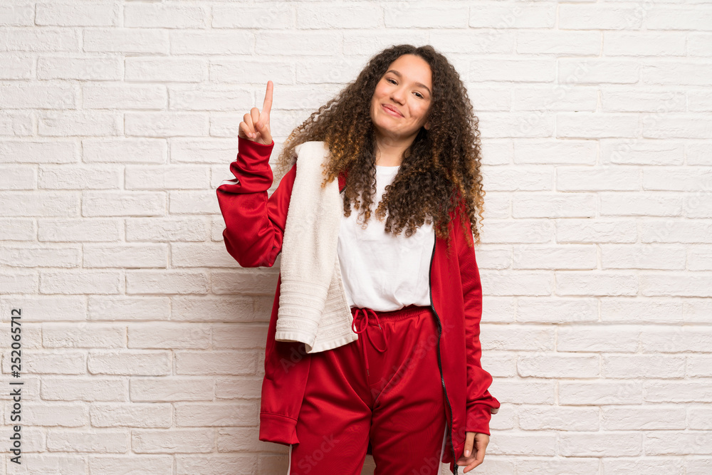 Teenager sport girl with curly hair showing and lifting a finger in sign of the best Teenager sport girl with curly hair showing and lifting a finger in sign of the best