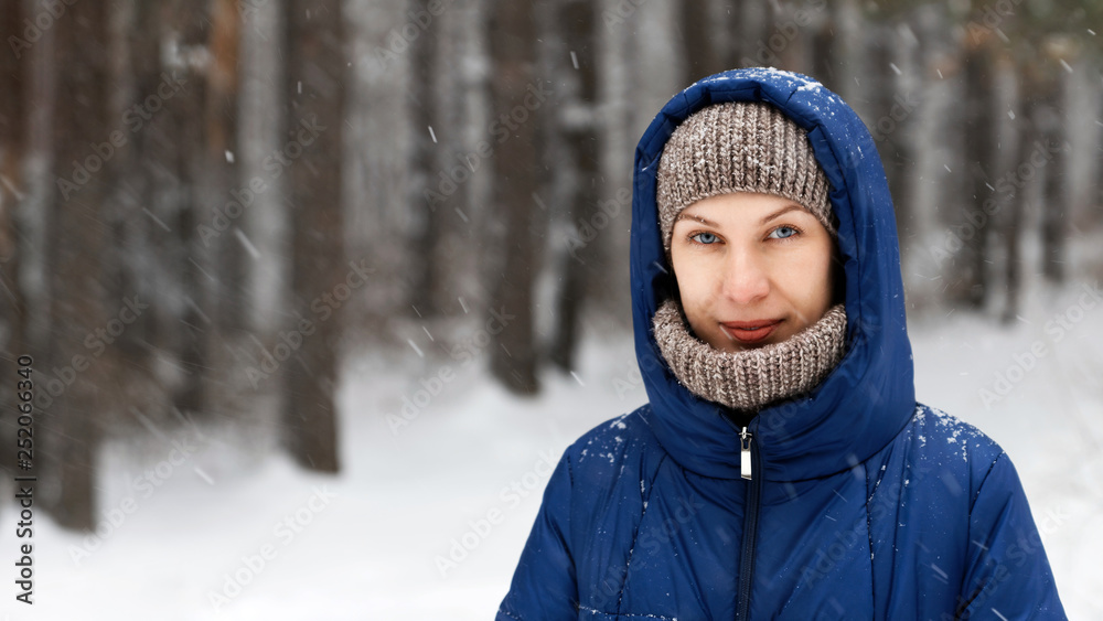 Portrait of a young woman surrounded by flying snowflakes on the background of a winter forest. Shallow focus. Portrait of a young woman surrounded by flying snowflakes on the background of a winter forest. Shallow focus.