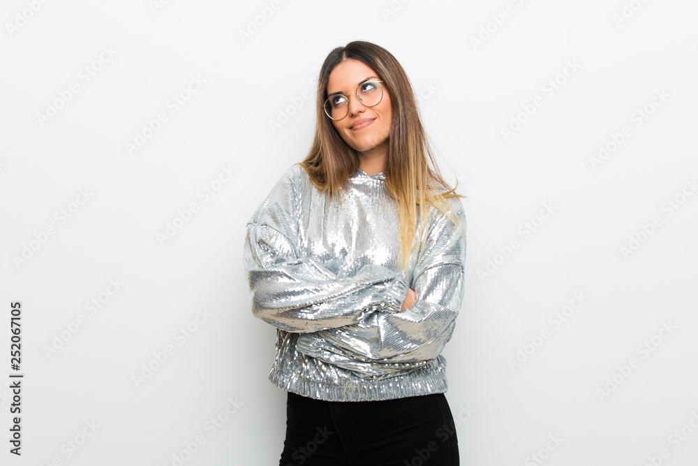 Young woman with glasses over white wall looking up while smiling Young woman with glasses over white wall looking up while smiling