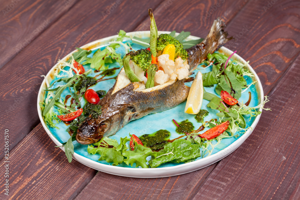 appetizing fried fish, beautifully laid out with greens and vegetables on a dish, for designer solutions in cooking appetizing fried fish, beautifully laid out with greens and vegetables on a dish, for designer solutions in cooking
