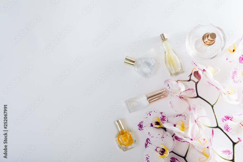 Bottles of perfume with white orchid with purple spots on white background. Space Bottles of perfume with white orchid with purple spots on white background. Space