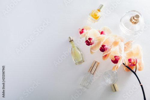 Bottles of perfume with orange orchid on white background. Space