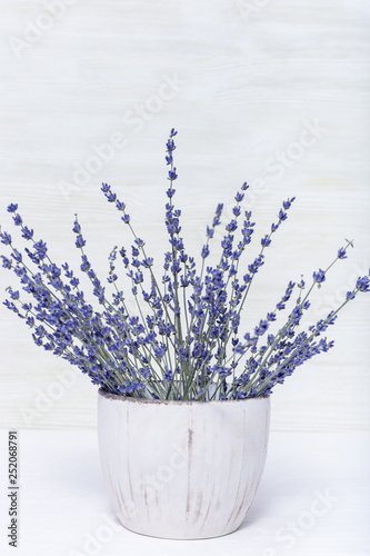 Natural lavender flowers in round vase on wood with copy space. Rustic flowerpot. Selective focus. photo