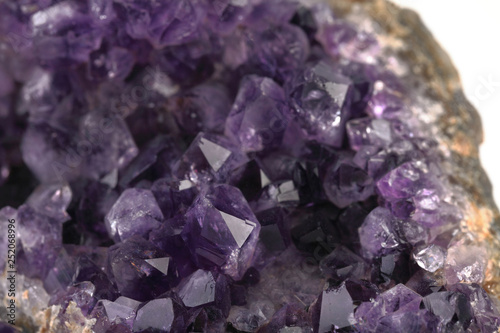 Beautiful amethyst druse close-up on white cement background. Semi precious gem used for jewels.