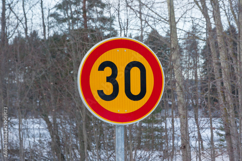 Speed limit 30 kilometers per hour road sign on trees background at winter in Finland. © Elena Noeva