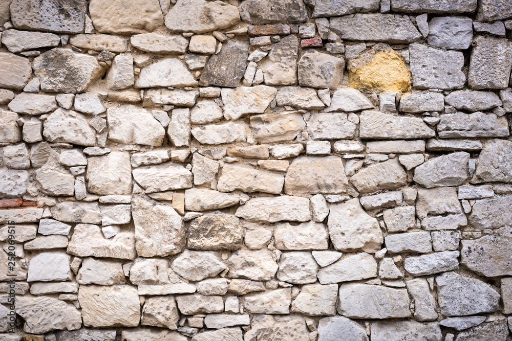 Fototapeta premium Eine Steinmauer mit vielen großen und kleinen Steinen als Hintergrund