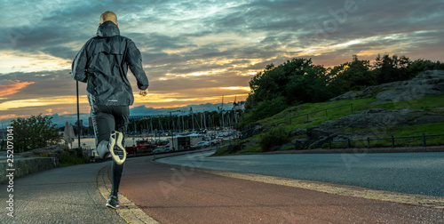 Back shot of running Caucasian Male in a City Park at night