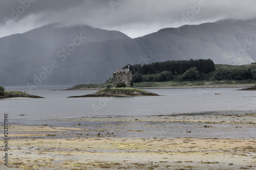 Iconic Castle Stalker, near Oban, watches Loch Linnhe and shows its unique 14th century tower under typical highlands dramatic sky