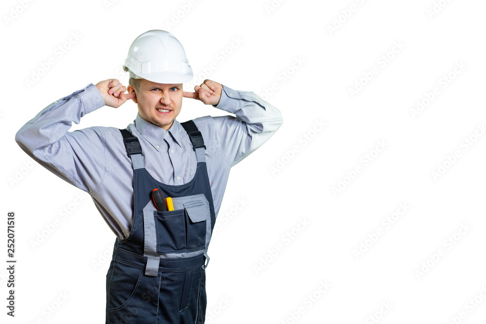A young construction engineer covers his ears with his hands. He is not happy with the noise level at the construction site. isolated A young construction engineer covers his ears with his hands. He is not happy with the noise level at the construction site. isolated