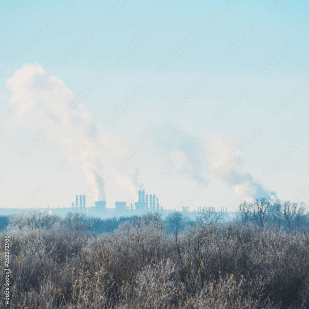 Modern landscape with factory pipes at a distance from which smoke is polluting the air
