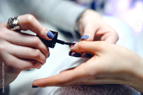 woman in a nail salon receiving a manicure nail gel polish by a professional beautician