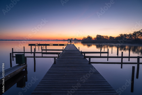 Man on a jetty  enjoying a tranquil dawn at the Leekstermeer  Holland.