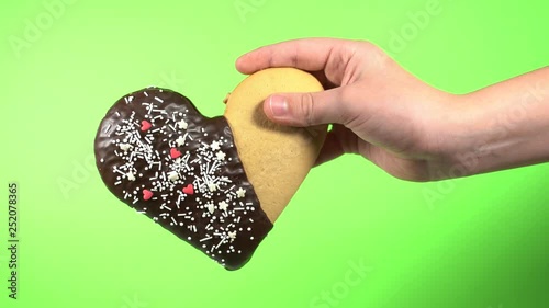 Closeup front view of cute small hands of young kid holding special sweet cookie in shape of heart. Happy Valentine day oy Mothres day holiday celebration concept. Real time 4k video footage. photo