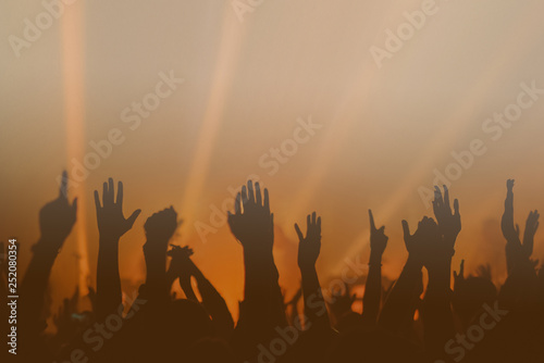 Hands silhouettes of the crowd raised up at music show. Colorful background