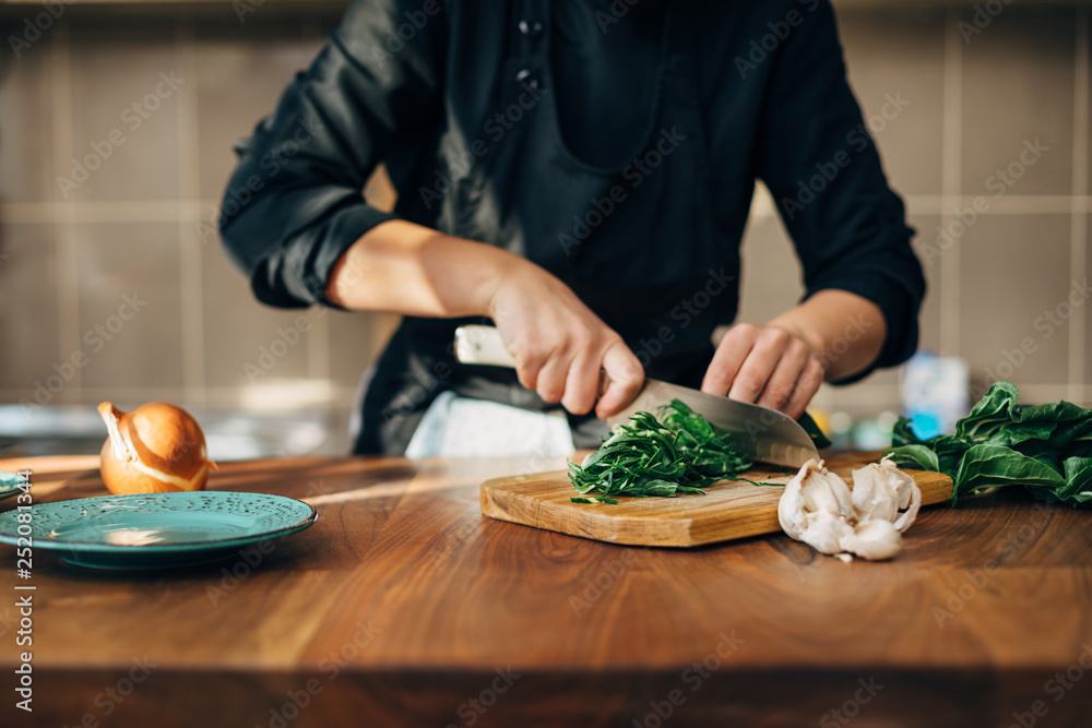 Female chef chopping raw vegetables on a wooden board Female chef chopping raw vegetables on a wooden board