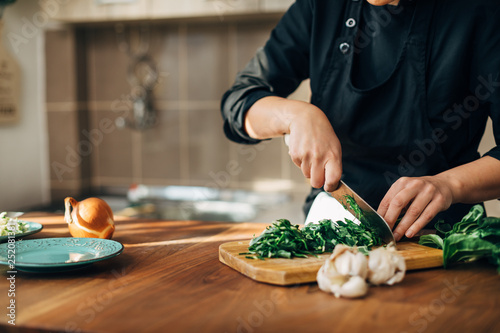 Female chef chopping raw vegetables on a wooden board