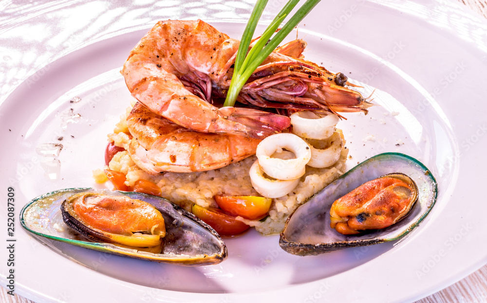 Fine dining mixed seafood set on the white plate, Shrimps, squids, green mussels Fine dining mixed seafood set on the white plate, Shrimps, squids, green mussels