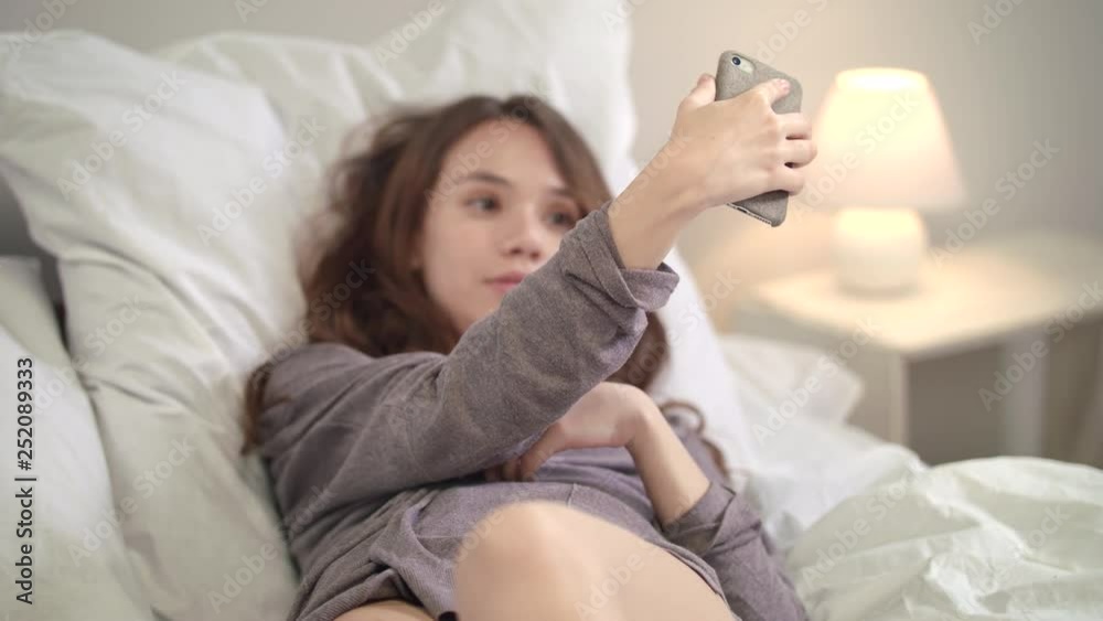 Sensual woman posing for mobile selfie in bed. Instagram blogging Sensual woman posing for mobile selfie in bed. Instagram blogging