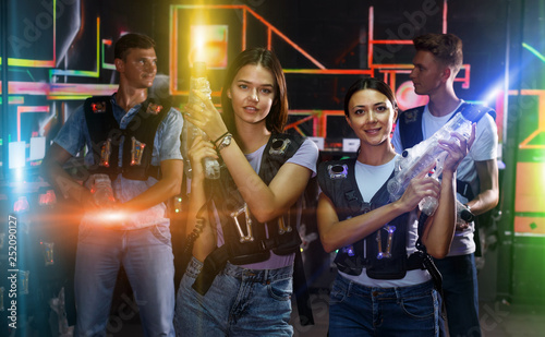 Two young women standing and holding guns during laser tag game