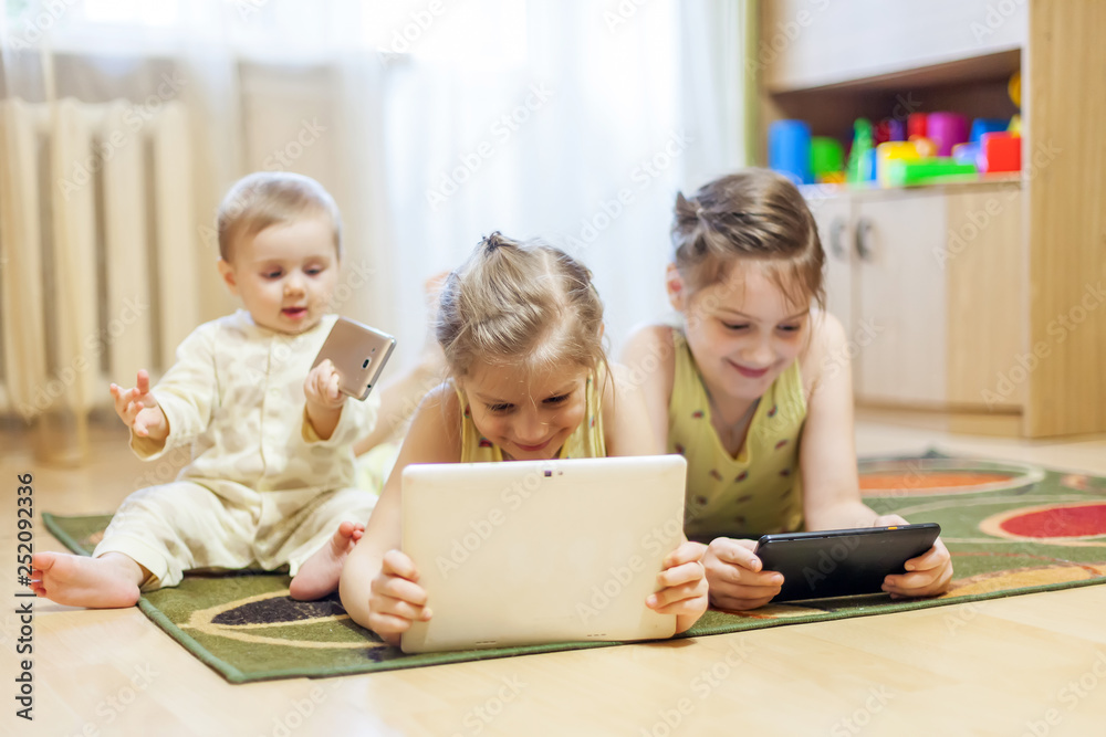 Little baby and older sisters playing tablets Little baby and older sisters playing tablets