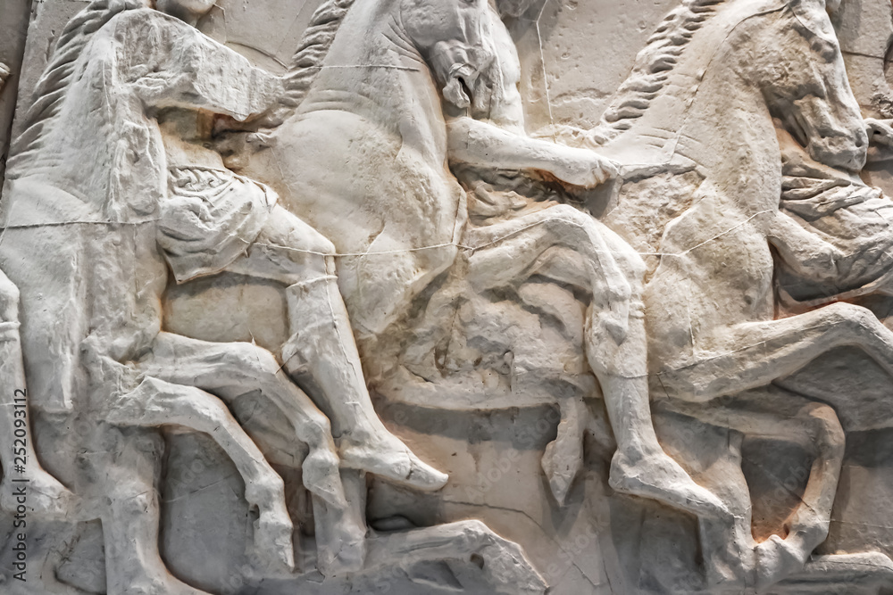 Background of horses in battle - cracked and mended white marble ancient bas relief sculptures from Greece