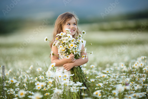 Little cute girl with bouquet of camomile flowers