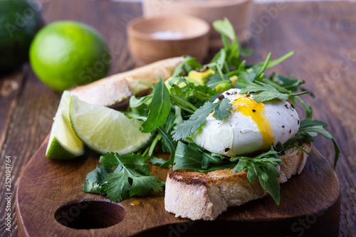 Vegetarian sandwich  with  poached egg, avocado, arugula  on toasted bread, healthy breakfast or snack
